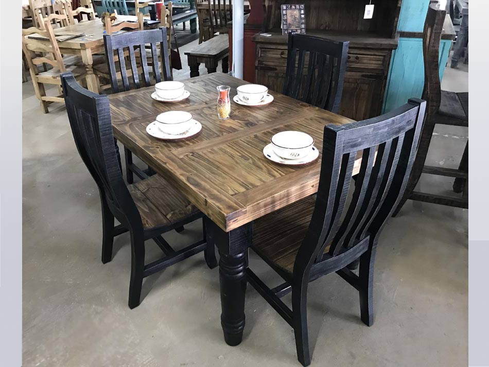 Angle view of rustic dining table in pine wood with black legs and chairs, available in Lubbock.